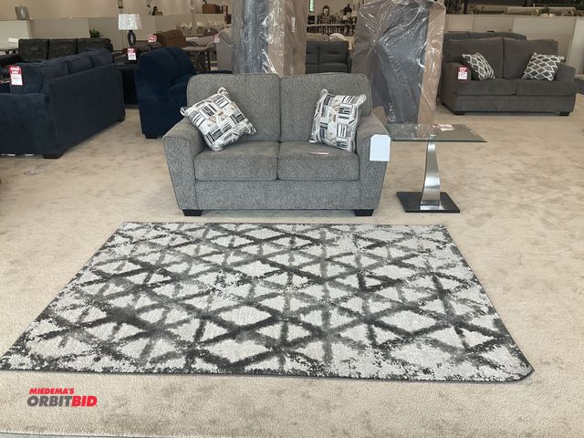 Lot 1-17163 - Gray loveseat, glass end table and rug. Love seat 60” by 37” deep. Rug is 91” by 62”. Table is 26” b...