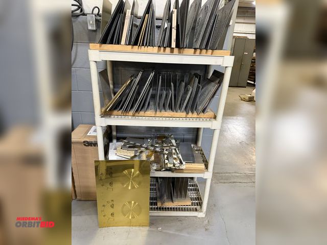 Lot 1-18976 - Large lot of dial face dies, includes aluminum, brass, and copper dies, with plastic shelving unit.