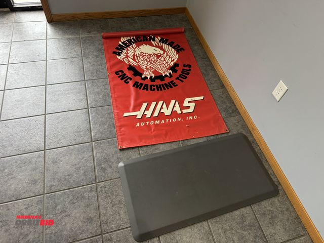 Lot 1-19592 - (1) 60" x 34" vinyl Haas CNC machine tools banner, and (1) approx. 20" x 39" ergonomic floor mat.