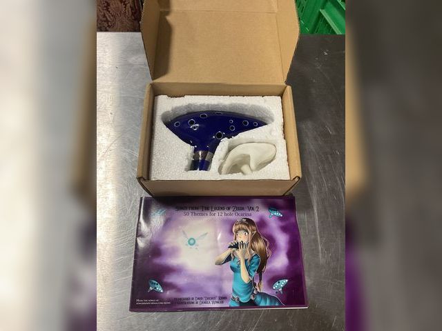 Lot 106-001222 - Legend of Zelda Ocarina. Comes with stand and song book. No damage. Mint condition.