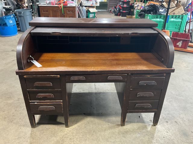 Lot 106-001187 - Dark brown wood roll top desk. Desk has multiple storage cubbies. 2 drawers on right side do not ope...