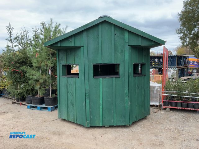 Lot 2-62922 - 8' x 8' green wooden deer blind with (7) lookouts (glass pieces for windows are included)