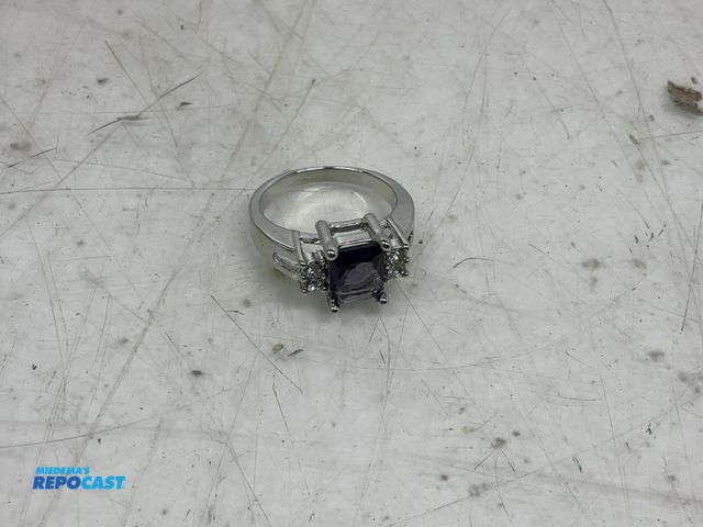 Lot 2-10055 - Rectangular purple gemstone in a silver tone setting ring size is unknown