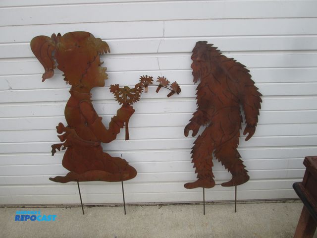 Lot 2-56972 - (2) Metal Silhouette Figures - Big Foot 45" h x 18" - Girl Blowing on Flowers - 48" h x 32"