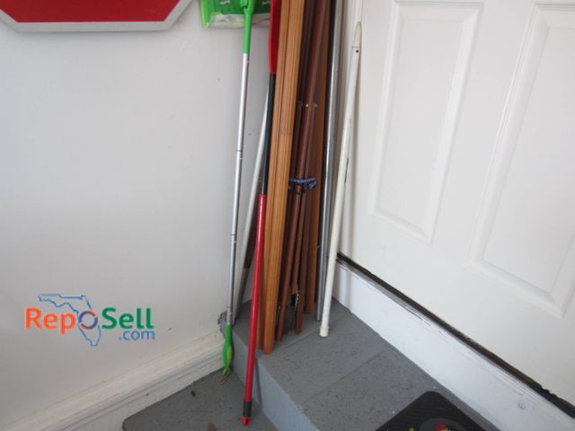Lot 31-9210 - Poles and handles, including wood, metal, and plastic types. Items appear to include a green mop han...