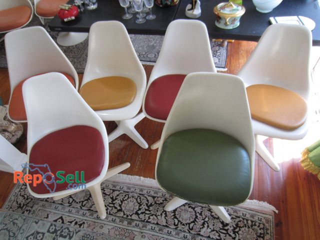 Lot 31-9117 - Six Tulip-Style White Plastic Chairs Featuring Red, Yellow, Green, And Orange Cushions.