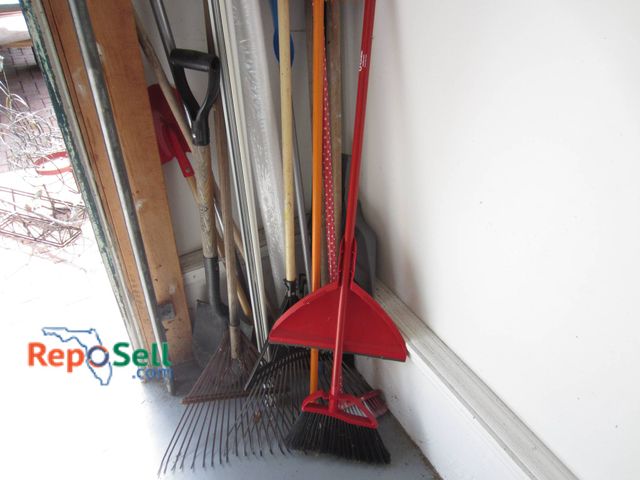 Lot 31-9201 - Yard tools, including multiple rakes, shovels, and brooms. Features a red dustpan and broom, a fruit...