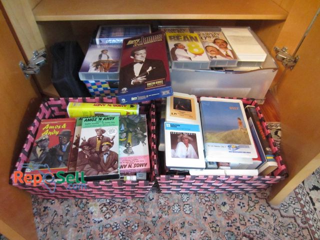 Lot 31-9235 - Media items stored in organized baskets and shelving. Includes VHS tapes, such as Amos 'N' Andy and ...