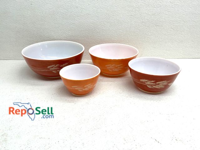 Lot 31-1400 - Four Pyrex mixing bowls in graduated sizes featuring an orange exterior with a white wheat pattern a...