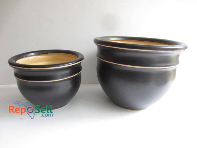 Lot 31-9243 - Two ceramic planters with a black exterior glaze and tan interior finish. Both feature a slightly ro...