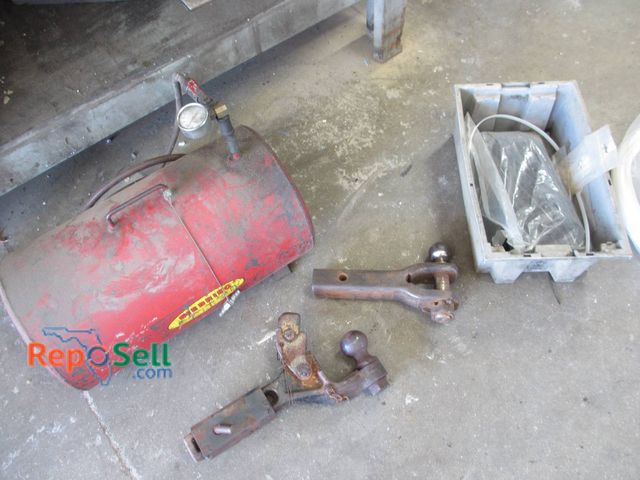 Lot 31-1311 - A Red Portable Air Tank With Attached Pressure Gauge And Valve, Along With Multiple Truck Hitches Fe...