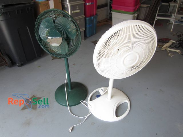 Lot 31-9206 - Two standing electric fans, one in green and the other in white, each featuring an adjustable height...