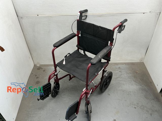 Lot 31-1461 - Red lightweight wheelchair featuring a foldable steel frame with black fabric upholstery. Equipped w...