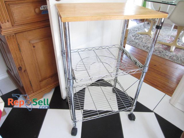 Lot 31-9169 - Rolling cart featuring a metal wire frame with two lower shelves and a wooden top surface. Equipped ...