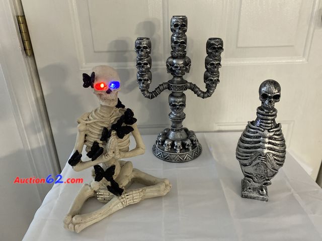 Lot 44-3631m - Skeleton with flashing eyes. Approximately 10”H X  8” W.  Skeleton statue. Approximately 9” H X 4” W. Skeleton candlestick. Holds 3 tapered ...