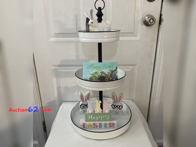 Lot 44-2127j - Appears to be new. White with black trim 3 tier decorative stand. Measures approximately 26” H X 14”W. Stuffed rabbit 5” long. Happy Easter ...