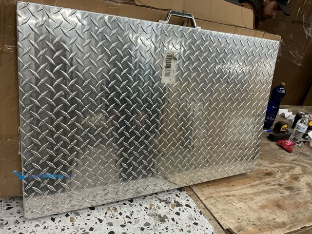 Lot 49-5459629 - Metal cover with handle. Diamond plate texture. 37x23. Slightly used, small dent.