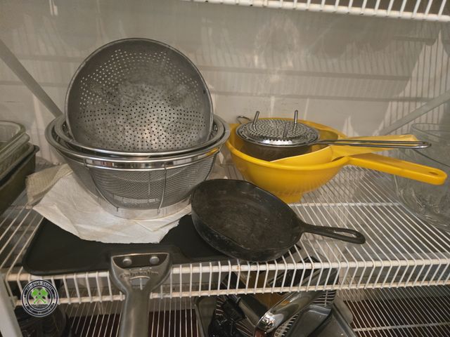 Lot 53-559 - Contents of shelf - Includes: Vintage Yellow Tupperware strainers, metal colanders, baking sheets, s...