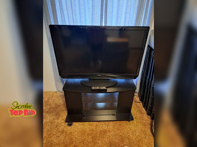 Lot 59-76030 - OFFSITE- 42" Flat screen Sanyo tv with remote and stand...Stand has 2 shelves on each side n 2 in mi...