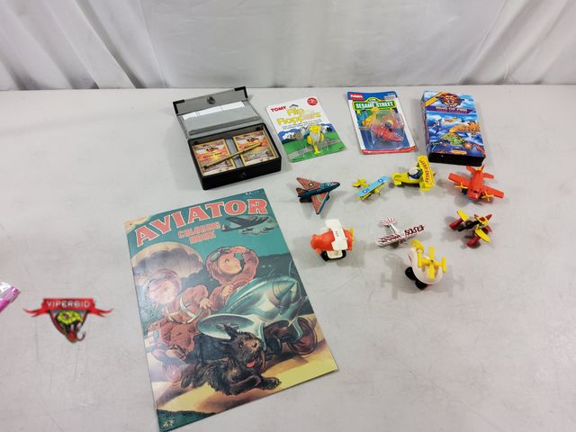 Lot 7-123583 - Airplane theme! Lot of assorted toy airplanes, vhs, metal sign, and a Red Baron Flight Deck card set...