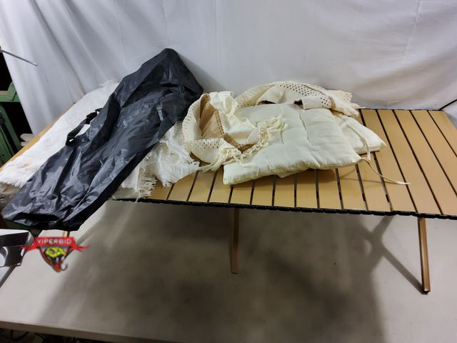 Lot 7-134423 - Portable metal table with Rolling table top and table clothes. (23-1/4"W x 59"L x 17-1/2T)