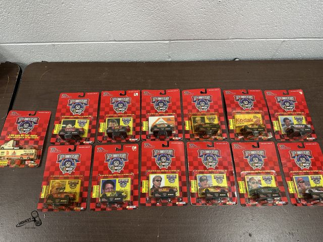 Lot 91-6607 - 13 TOTAL 50TH ANNIVERSARY NASCAR 1:64 SCALE DIE CASE REPLICA WITH COLLECTOR CARD AND DISPLAY STAND -...